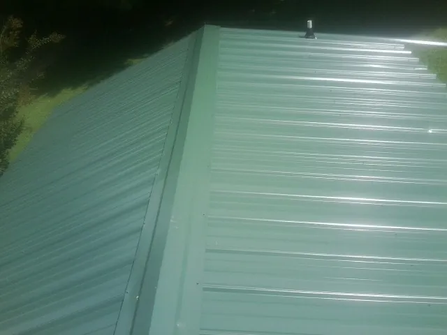 New green metal panels meeting at the ridge of a roof — Flat Roof Repair work by our crew in Green Pond
