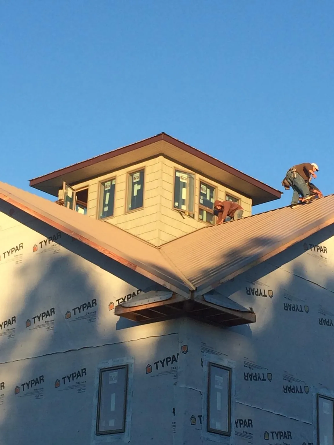 Roofers working around a rooftop cupola on a new metal roof at sunset — Roof Waterproofing in Green Pond by Roofing Brothers